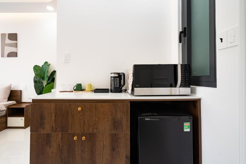 In-room kitchenette counter with microwave and mini-fridge at Ekomo Home 95 - Metro Ben Thanh